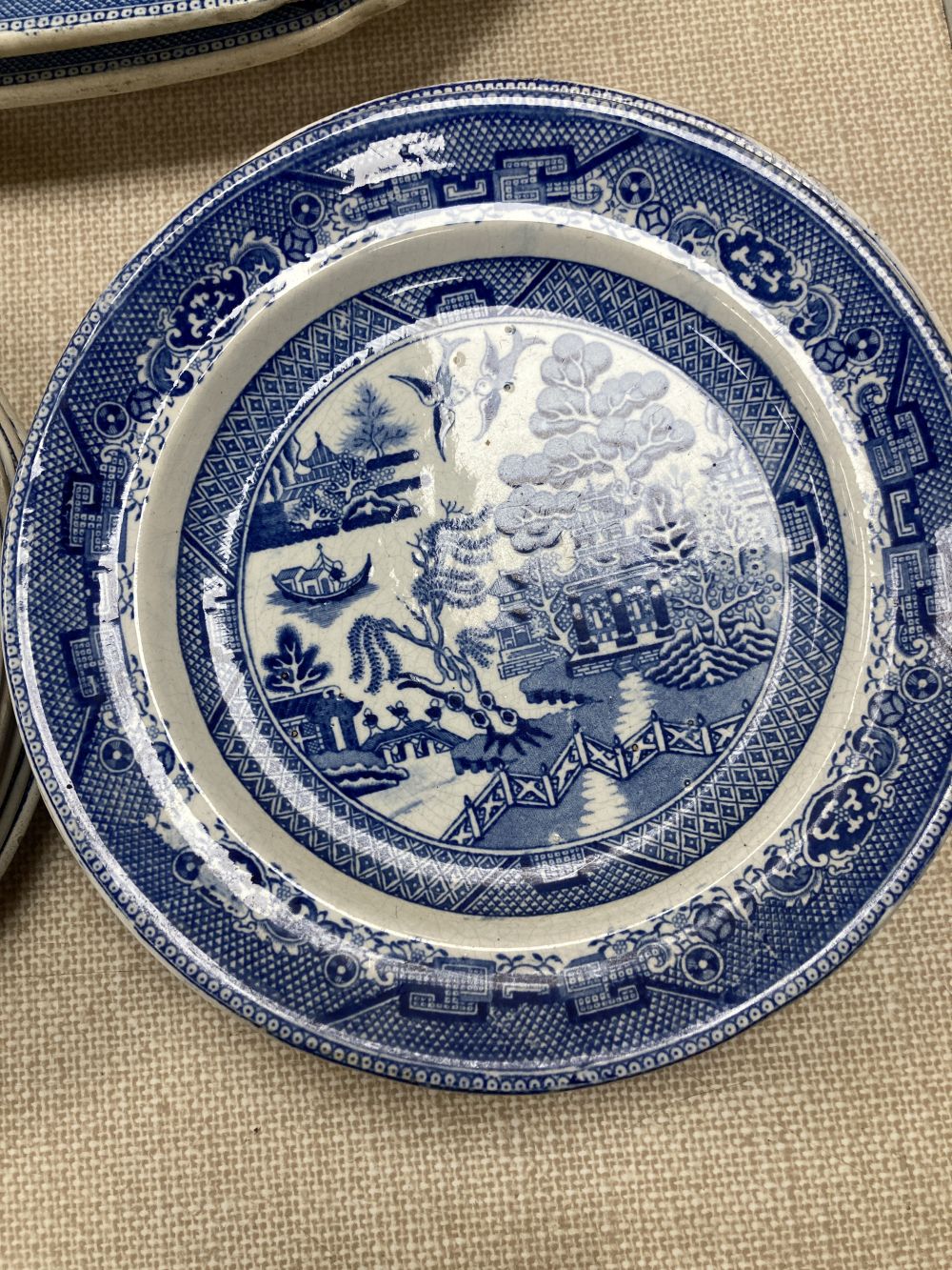 A collection of blue and white Willow pattern plates including meat platters, width 44cm and a tureen